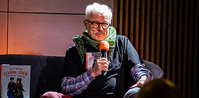 Krzysztof Deszczyński na żółtej sofie w Książnicy Beskidzkiej